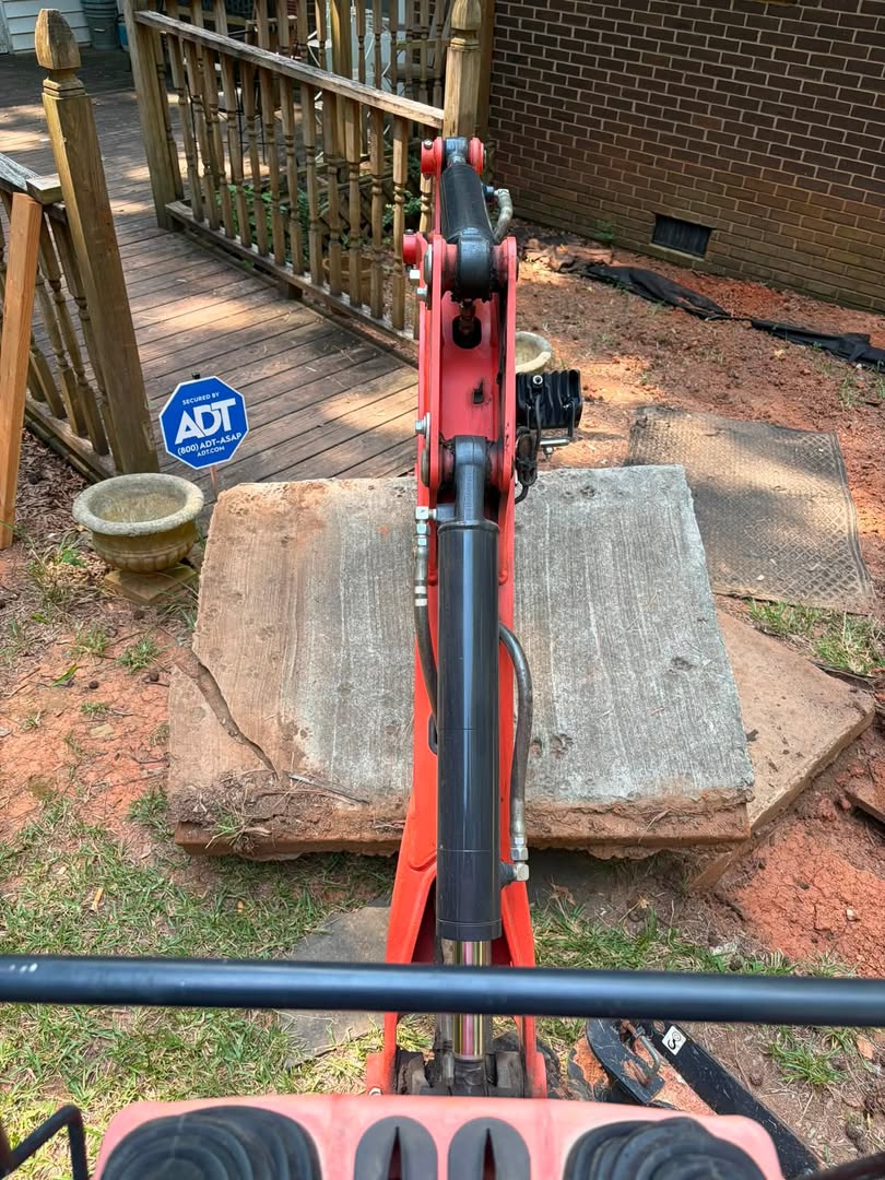 Mini-excavator arm over a concrete septic lid